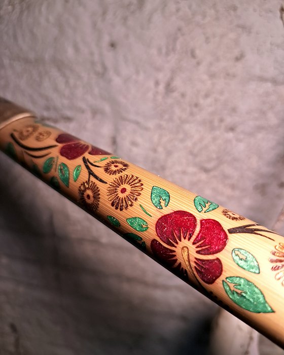 Detalhe do bambu decorado com flores vermelhas e folhas verdes.