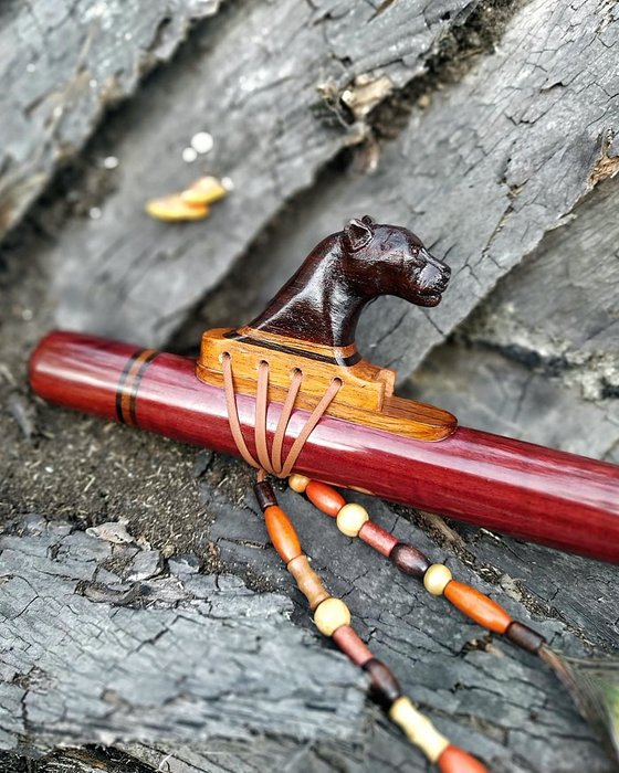 Flauta nativa com totem de abelha, contas e penas.
