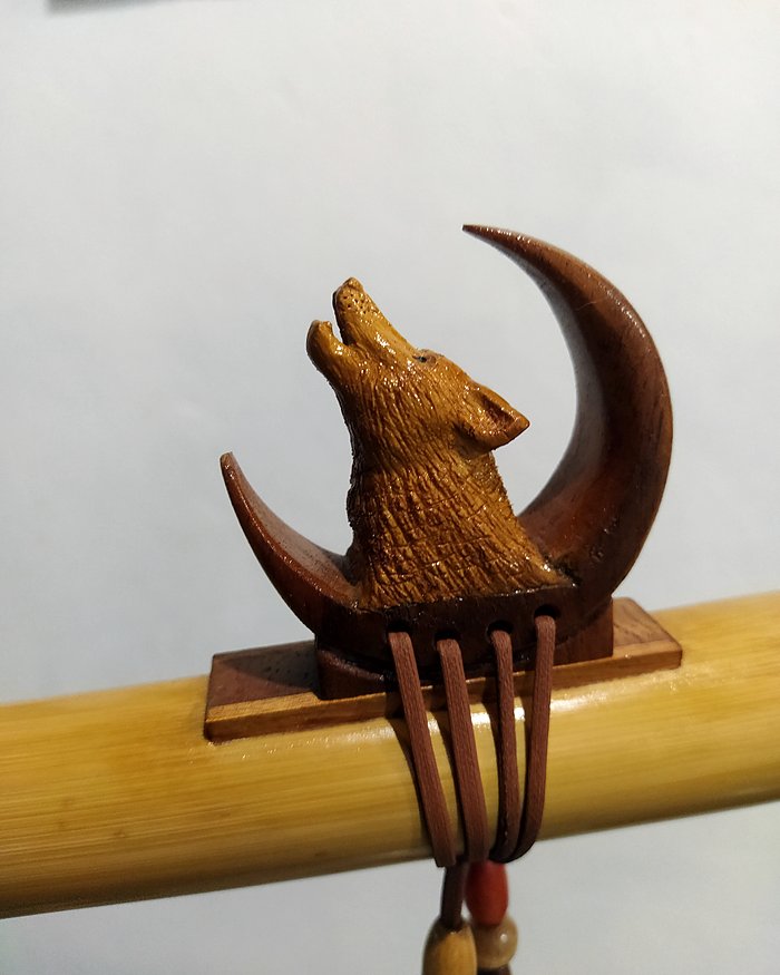 Totem de lobo uivando para a lua, sobre flauta nativa de bambu.