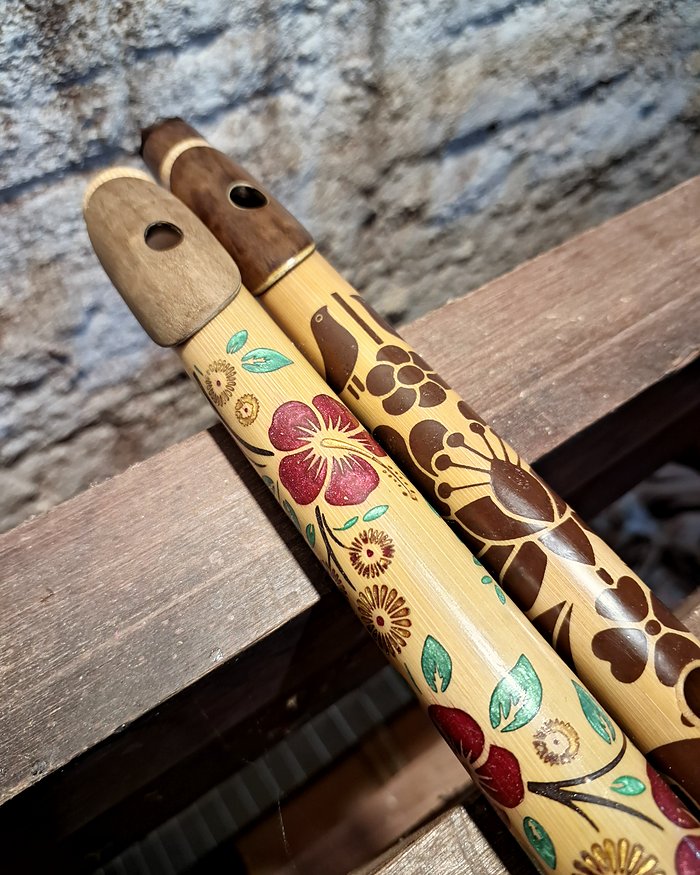 Duas flautas de bambu decoradas com flores.