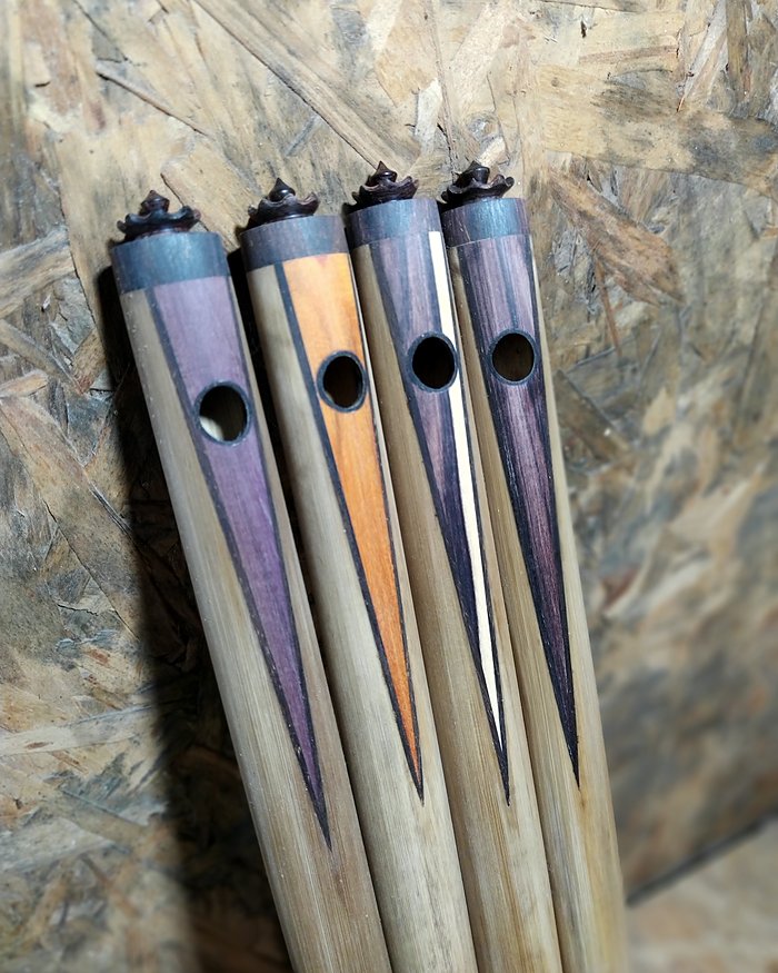 Quatro flautas de bambu com embutidos coloridos e coroas.